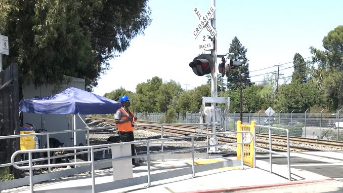 ON DUTY — A Cypress Security guard keeps an eye on the Caltrain crossing at Charleston Road in Palo Alto. Post file photo.