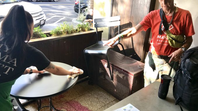 John King points to where robbers grabbed a laptop at Starbucks on University Ave. in Palo Alto. Post photo by Sara Tabin.