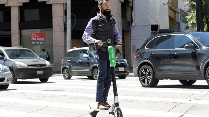 A man on an e-scooter buzzes along Market Street in San Francisco in this 2018 AP file photo.