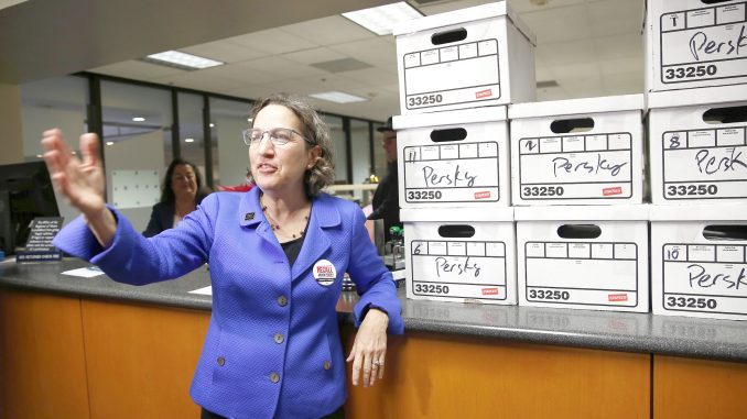 Michele Dauber, standing at the counter of the Registrar of Voters in San Jose on Jan. 11, gestures to supporters after handing over boxes containing signatures to place the recall of Santa Clara County Judge Aaron Persky on the June ballot.