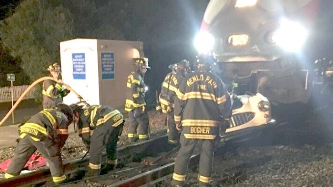 Menlo Park firefighters work to remove a 1950s-era Austin Healey convertible from the front of a Caltrain at the Watkins Avenue crossing Saturday night. Photo provided by the Menlo Park Fire Protection District.