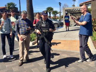 A Palo Alto police officer walks through Town & Country Village Shopping Center just after a lockdown ended at Palo Alto High School across the street. Post photo by Allison Levitsky.