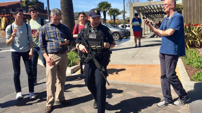 A Palo Alto police officer walks through Town & Country Village Shopping Center just after a lockdown ended at Palo Alto High School across the street. Post photo by Allison Levitsky.