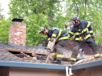 Firefighters from San Mateo Truck 21 cut a ventilation hole to help access an attic fire in a Menlo Park home Saturday evening. Photo by Peter Mootz.