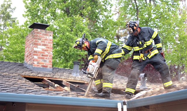 Firefighters from San Mateo Truck 21 cut a ventilation hole to help access an attic fire in a Menlo Park home Saturday evening. Photo by Peter Mootz.