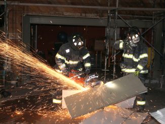 Firefighters cut apart a garage door so that other firefighters can gain access to the fire in a room and stairway behind the garage at 50 La Loma Drive in Menlo Park. Photo by Peter Mootz, courtesy of the Menlo Park Fire Protection District.