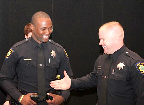 Tom DeStefano, right, puts his hand out to former Palo Alto police officer Marcus Barbour in this 2014 photo posted on social media by the Palo Alto Police Department.