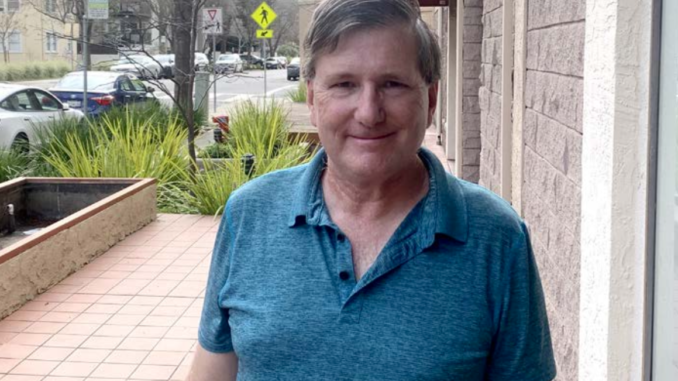 Karl Ryan, a middle-aged white man in a blue polo shirt, stands outside.